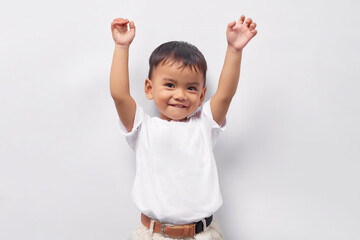 Excited Toddler Asian kid boy 2 years old wearing a white t-shirt raising a fist, celebrating...