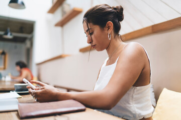 Obraz premium Young ethnic woman using smartphone in cafe
