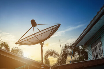 A Black Satellite dish on roof for TV channe with country house in blue sky with dramatic sunset sky Background in thailand