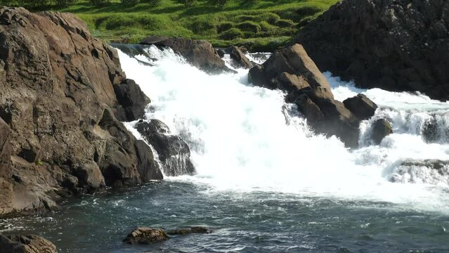 Glanni Waterfall with jumping salmon during summer in Iceland. Magical Icelandic landscape with lush green bushes. High quality 4k footage