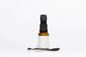 Fototapeta na wymiar Mockup of amber colored glass bottle of cosmetic and facial care and skincare products, with facial applicator, on a white background