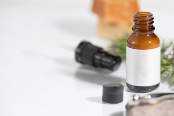 Mockup of open amber colored glass bottle of cosmetic and facial care product, with green leaves