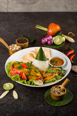 Grilled fillet fish tilapia with curry spicy sauce, cucumber, tomato and steamed rice in white plate.