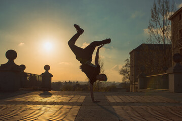 teenager boy with blue hair and sportswear dancing breakdace on the street. hip hop culture. street dancer doing pirouettes and stunts. © Alberto