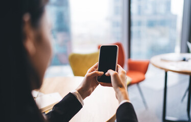 Crop woman using smartphone in office