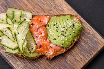 Delicious brown bread toast with salmon, avocado, cucumber and sesame seeds
