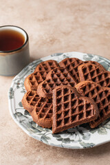 Heart form chocolate waffle cookies in festive plate for Valentine's day with tea on beige background. Gift with love for Valentine's Day