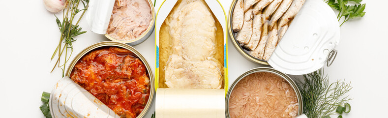 Canned fish assortment on white background, processed food.