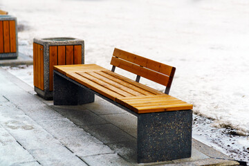 Park bench made of wood and granite in winter some snow