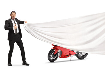 Man in a suit and tie holding a white piece of cloth in front of a red motorbike