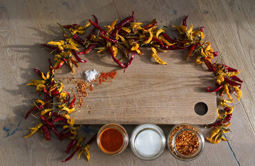 Dried chilies placed on a wooden chopping board, with chilli powder, salt and seeds. A colourful...