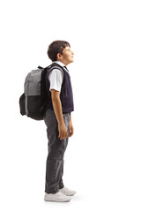 Full length profile shot of a boy in a school uniform carrying a backpack and looking up