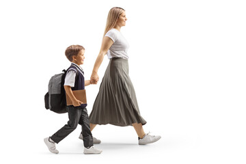 Full length profile shot of a mother and schoolboy walking and holding hands