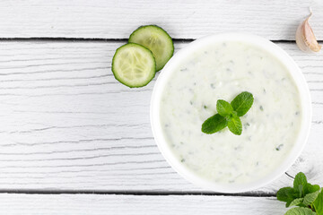 Indian raita sauce with yogurt, cucumber and herbs on a white background. Top view. Indian food. Greek tzatziki sauce.