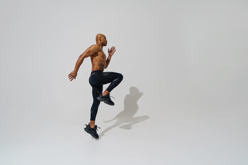 Fototapeta na wymiar Professional male athlete running isolated on white studio background with shadows