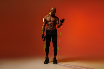Fototapeta na wymiar Sporty man performs exercises with expander on studio background. Strength and motivation