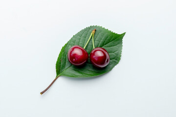 Ripe cherries lie on a cherry leaf.Top view on a white background.
