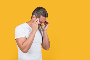 stressed man in shirt has migraine isolated on yellow with copy space. stressed man with migraine
