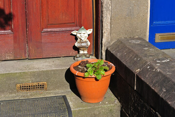 Close Up of Cute Figure and Plant Pot on Stone Step of Old House