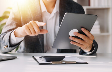Asian Business woman using calculator and laptop for doing math finance on an office desk, tax, report, accounting, statistics, and analytical research concept