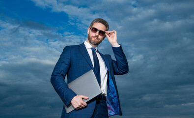 Professional man in suit fixing glasses. Professional businessman holding laptop. Business professional