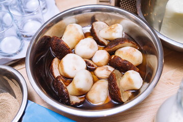 Fresh large porcini mushrooms in a metal bowl on a kitchen table