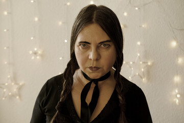 portrait of mature woman in gothic style dressed Wednesday Addams during Halloween, black clothes,...