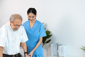 Happy smiling nurse in hospital and clinic uniform helping senior man with spectacles walk using a walker in the passage and corridor after successful treatment and physiotherapy