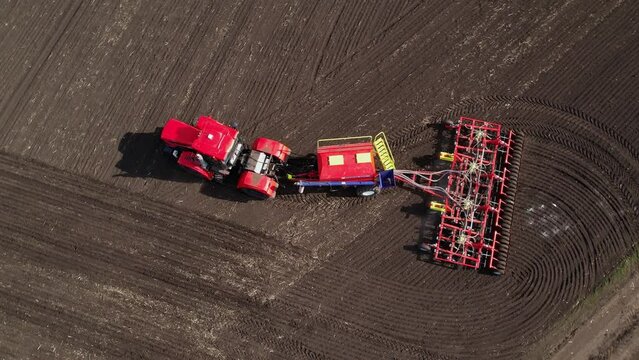 Tractor with a seeder in an agricultural field, aerial view. The season of sowing grain crops. Tillage for sowing. Agricultural work. Farming industry. Top view