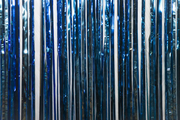 Blue tinsel on white wall as an abstract background