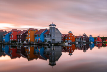 Multicolour harbourside row houses at sunset. Long exposure and reflection in water.