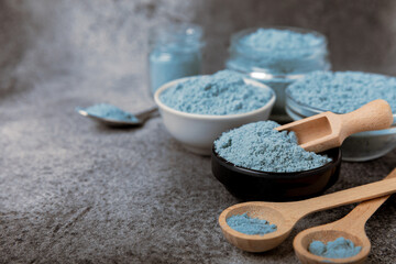 Blue spirulina powder in bowls on black texture background. Natural vegan superfood. Food supplement. Phycocyanin extract. Healthly food. Place for text. Copy space.