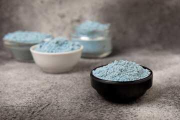 Blue spirulina powder in bowls on black texture background. Natural vegan superfood. Food supplement. Phycocyanin extract. Healthly food. Place for text. Copy space.