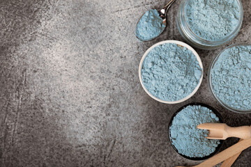 Blue spirulina powder in bowls on black texture background. Natural vegan superfood. Food supplement. Phycocyanin extract. Healthly food. Place for text. Copy space.