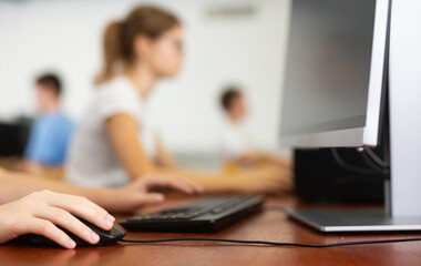 Fototapeta na wymiar Closeup schoolgirl using computer mouse with computer keyboard in computer class