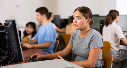 Focused female teenager solving tasks of computer science in the auditory
