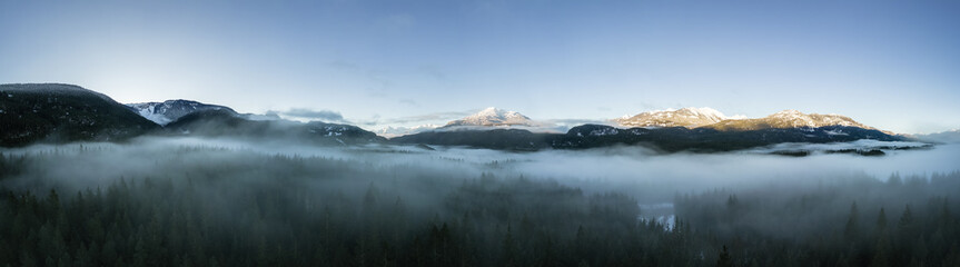 Obraz na płótnie Canvas Green Trees in Forest with Fog and Mountains. Winter Sunny Sunrise. Canadian Nature Landscape Background. Near Squamish, British Columbia, Canada. Panorama