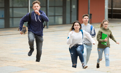 Fototapeta premium Group of teenage friends running as they leave the school building after lessons
