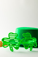 Image of green hat, green clover glasses, gold necklace and copy space on white background
