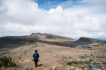 Fototapeta premium Woman walking through paramo mountain path in a cloudy day