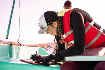 Marine biologist writing data on top of a boat - obrazy, fototapety, plakaty
