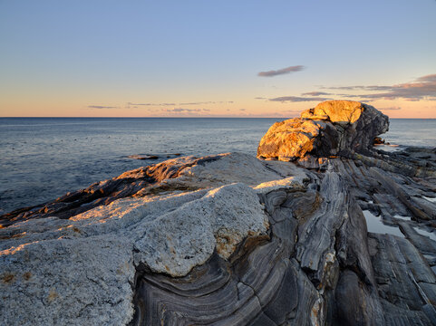 Sunrise lights up the unique rock strata at Pemaquid Point near the Lighthouse in the state of Maine