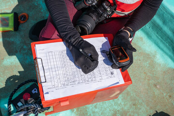 Unrecognizable marine biologist writing data on paper on a boat - obrazy, fototapety, plakaty