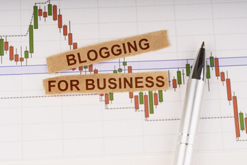 On the chart of business quotes lies a pen and torn paper with the inscription - Blogging for Business