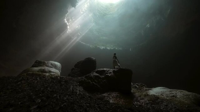 Woman Posing On Rock While Sunrays Passing In Sinkhole Cave At Vacation - Java, Indonesia
