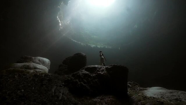 Female Tourist Dancing On Rock In Ancient Cave During Vacation - Java, Indonesia