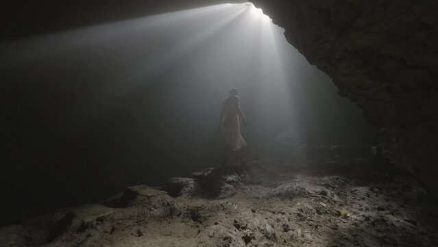 Sunrays Falling On Woman Walking In Deep Cave While Exploring During Vacation - Java, Indonesia