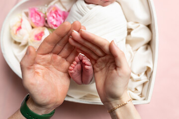 Children's feet in the hands of parents. Legs of a tiny newborn in the arms close-up. Family and child. Happy family concept. Beautiful concept image of motherhood