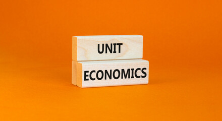 Unit economics symbol. Concept words Unit economics on wooden blocks. Beautiful orange table orange background. Business and unit economics concept. Copy space.