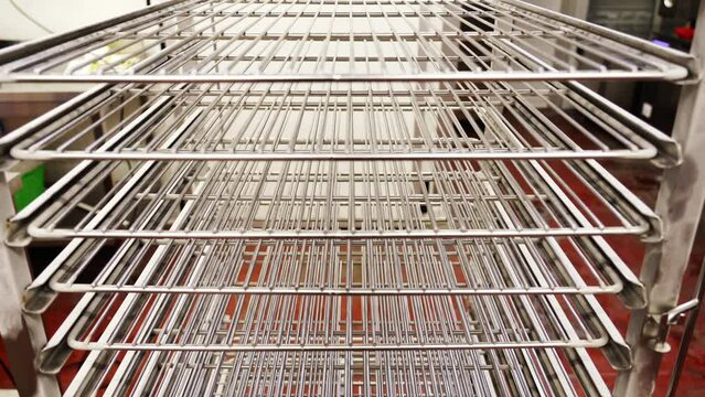 Contemporary rack with group of empty shiny metal shelves stands in brightly lit supermarket warehouse extreme close view